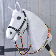 Light grey Hobby Horse in a black halter wearing the braided black, red and yellow Reins Flag around its neck