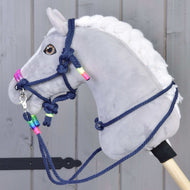 The Rope set Rosemary by Hobby Horse LarDen features a gray plush hobby horse with a white mane, navy blue reins and halter with neon beads, mounted on a wooden stick in front of a gray wooden background.