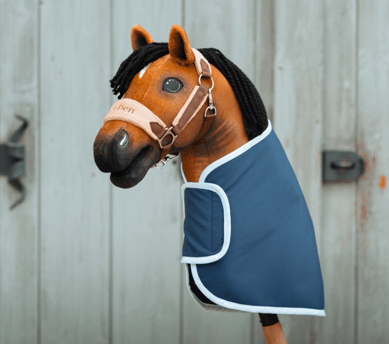 LarDen Hobby Horse iført et blåt dækken med hvid kant og en grime