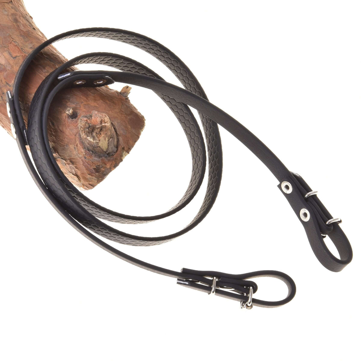 The Rubberized reins black by Hobby Horse LarDen are looped around a piece of wood and displayed on a white background, showcasing their sleek black finish and textured detailing reminiscent of classic reins.