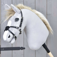 The Hobby Horse LarDen "Noseband Mexico Black" is a gray plush hobby horse with a black bridle, leatherette noseband, and light mane on a stick, shown before a gray wooden wall.