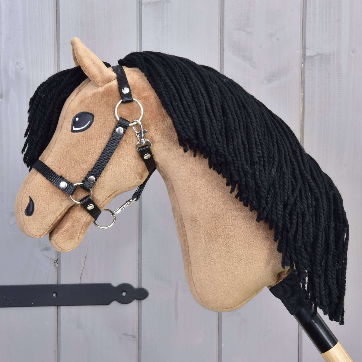 The Hobby Horse Samantha with Black Halter by Hobby Horse LarDen features a tan face, black yarn mane, stitched details, and a black halter, presented on a light wooden background.