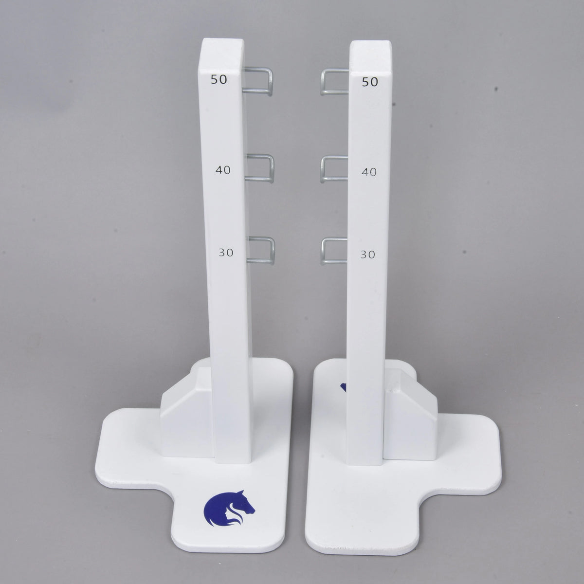 The Hobby Horse LarDen Jump 50 cm / 20 inch features two white vertical stands with measurement marks at 30, 40, and 50 cm, metal hooks on each side, a blue horse logo on sturdy bases—ideal for adjustable hobby horsing jumps indoors or outdoors.