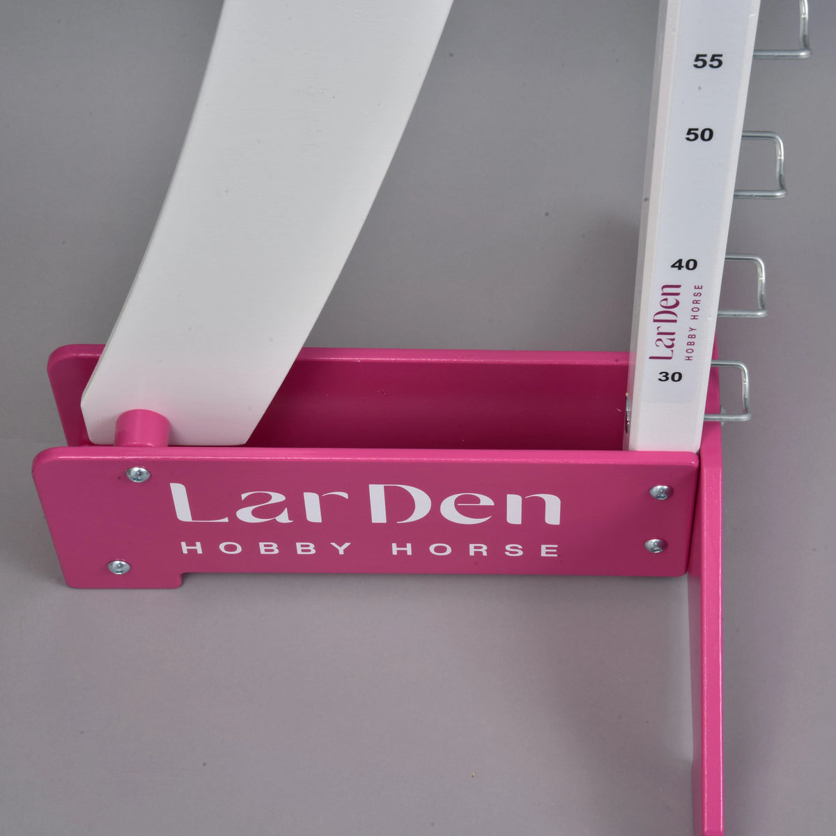 Detalje af en lyserød fod med den hvide skrift LarDen Hobby Horse, som holder standeren med markeringer fra 30 til 55 cm