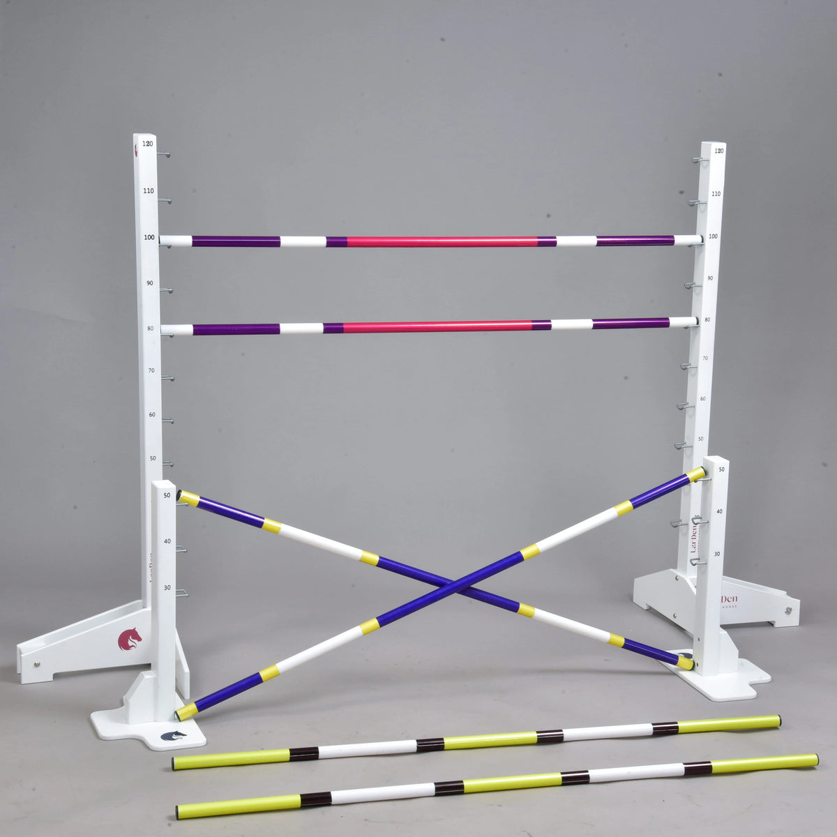 The Hobby Horse LarDen Jump set for Hobby Horsing includes white standards with measuring marks, four colored poles (two horizontal and two crossed), and two yellow-and-black cavaletti in front, shown against a plain gray background.