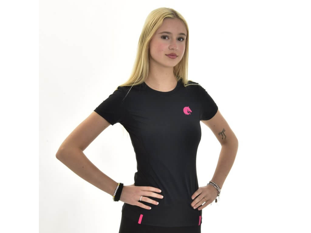 A young woman with long blonde hair stands against a white background, wearing the Hobby Horse LarDen "T-Shirt LarDen Active Black" featuring a pink logo and accents. She poses with hands on her hips, highlighting the spandex fabric and bracelets.