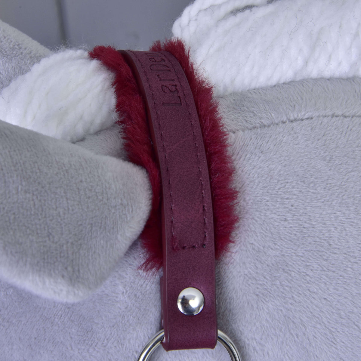 Close-up of a plush grey fabric with a white rope and maroon leatherette halter strap with fuzzy red edges, secured by silver hardware—a stylish “Halter with fur - leatherette Burgundy” from Hobby Horse LarDen.