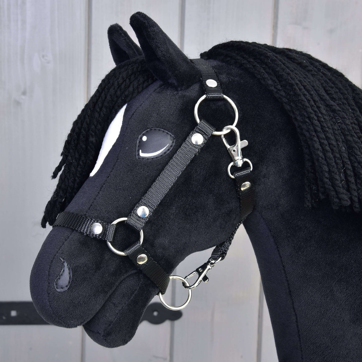 The Hobby Horse Cloony with Black Halter by Hobby Horse LarDen is a black fabric horse styled as an American Quarter Horse stallion, featuring a white spot near its eye, black yarn mane, and photographed against light wood.