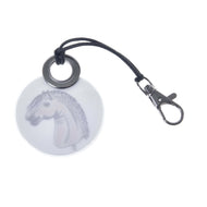 The Keychain round LarDen by Hobby Horse LarDen features a horse’s head on a stick illustration, inspired by hobby horsing, with a black cord and metal clasp—an ideal playful accessory for fans.