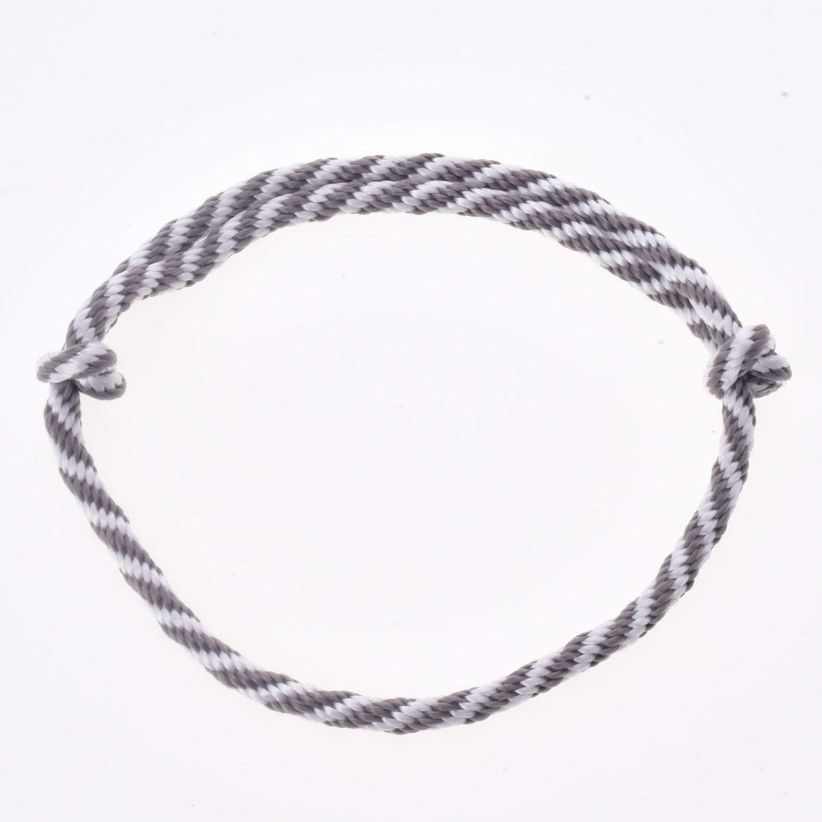 A gray and white twisted rope, forming a circle with simple knots at each end and set against a plain white background, makes up the "Set Start Silver" (halter + cordeo + lead rope + reins) from Hobby Horse LarDen—ideal for use as reins or halter and leash accessories for your hobby horse.