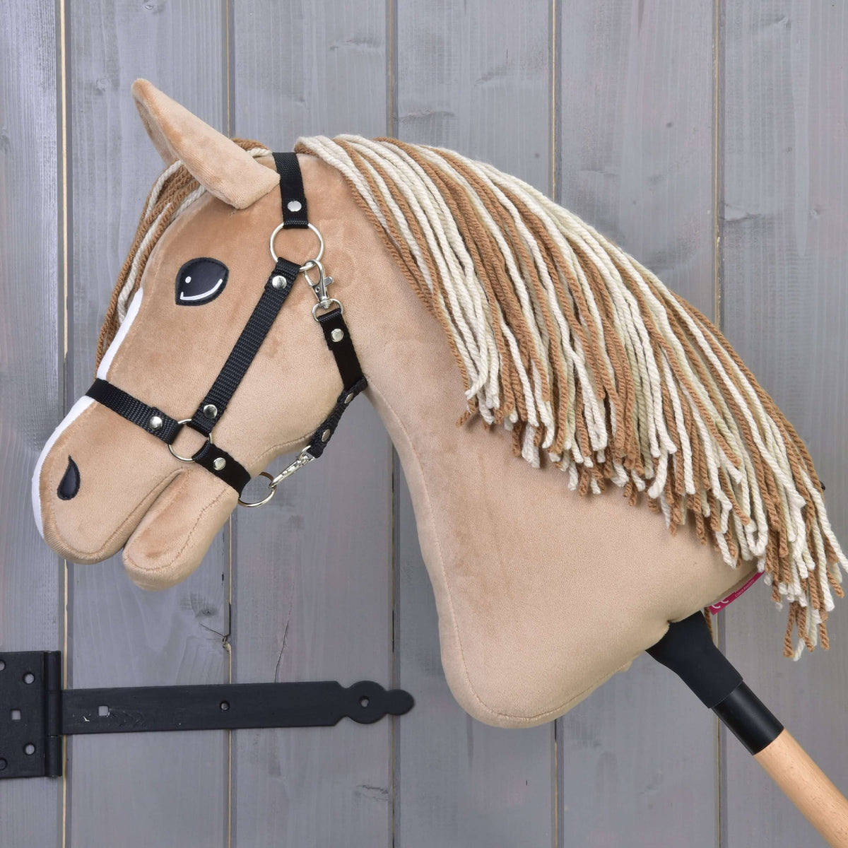 Hobby Horse Bren med sort grime set fra siden med sænket hoved og lang manke af brunt og cremefarvet garn