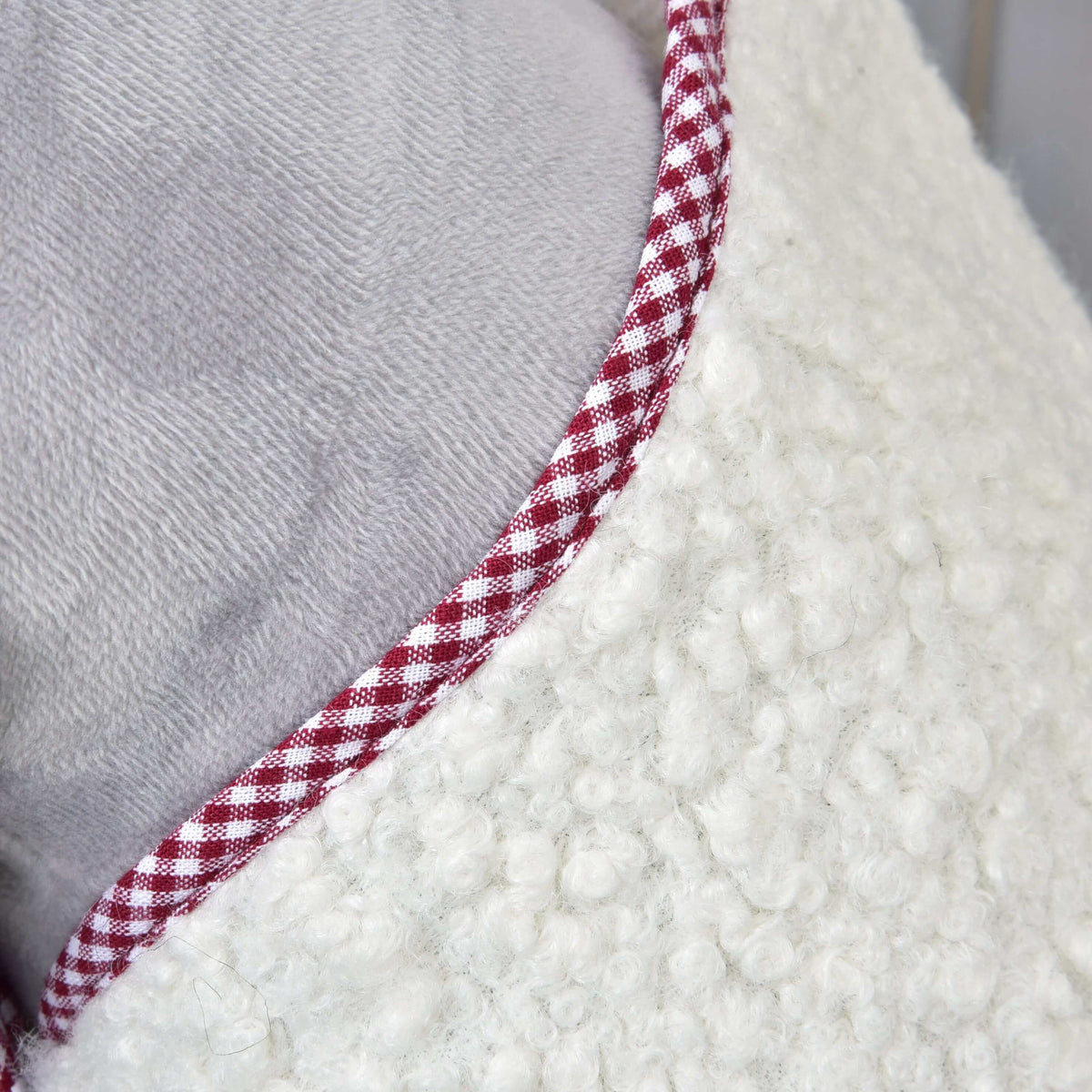 Close-up of Hobby Horse LarDen's Blanket cube red: textured white fabric with a fluffy surface, red and white checkered trim, and smooth gray back—perfect for stylish comfort and protection on your hobby horse.
