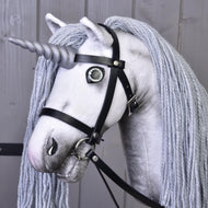 The Hobby Horse LarDen Hobby Horse Unicorn Silver with Bridle and Halter features a magical unicorn head with a silver horn, long gray yarn mane, and black leather bridle, set against a wooden background.