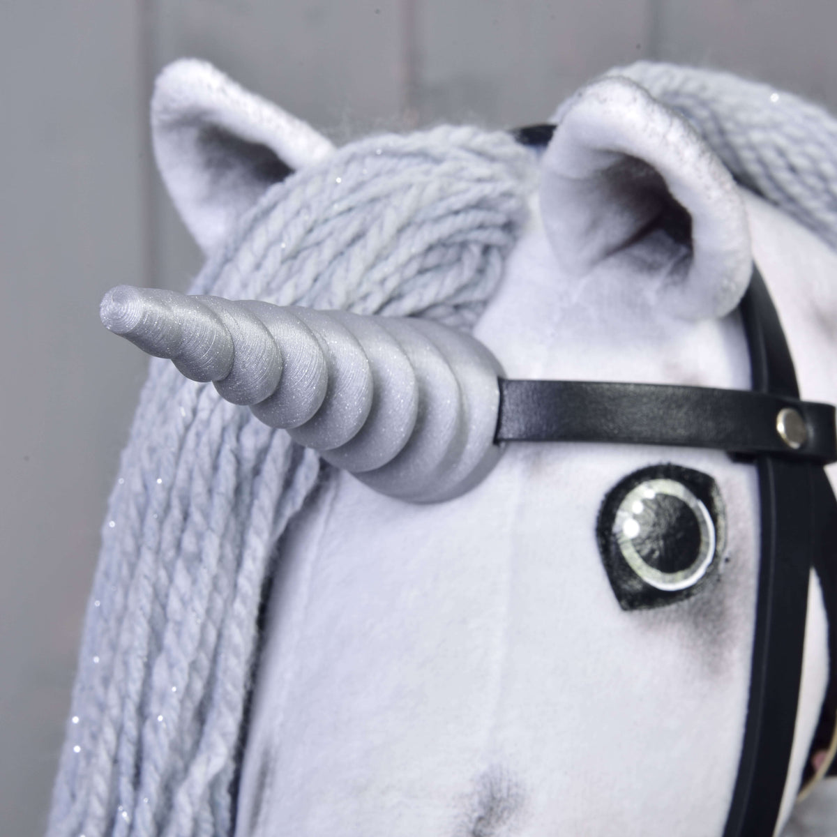 Tæt på det sølvfarvede spiralhorn på Hobby Horse enhjørning Silver, fastgjort til den sorte trense mellem ørerne