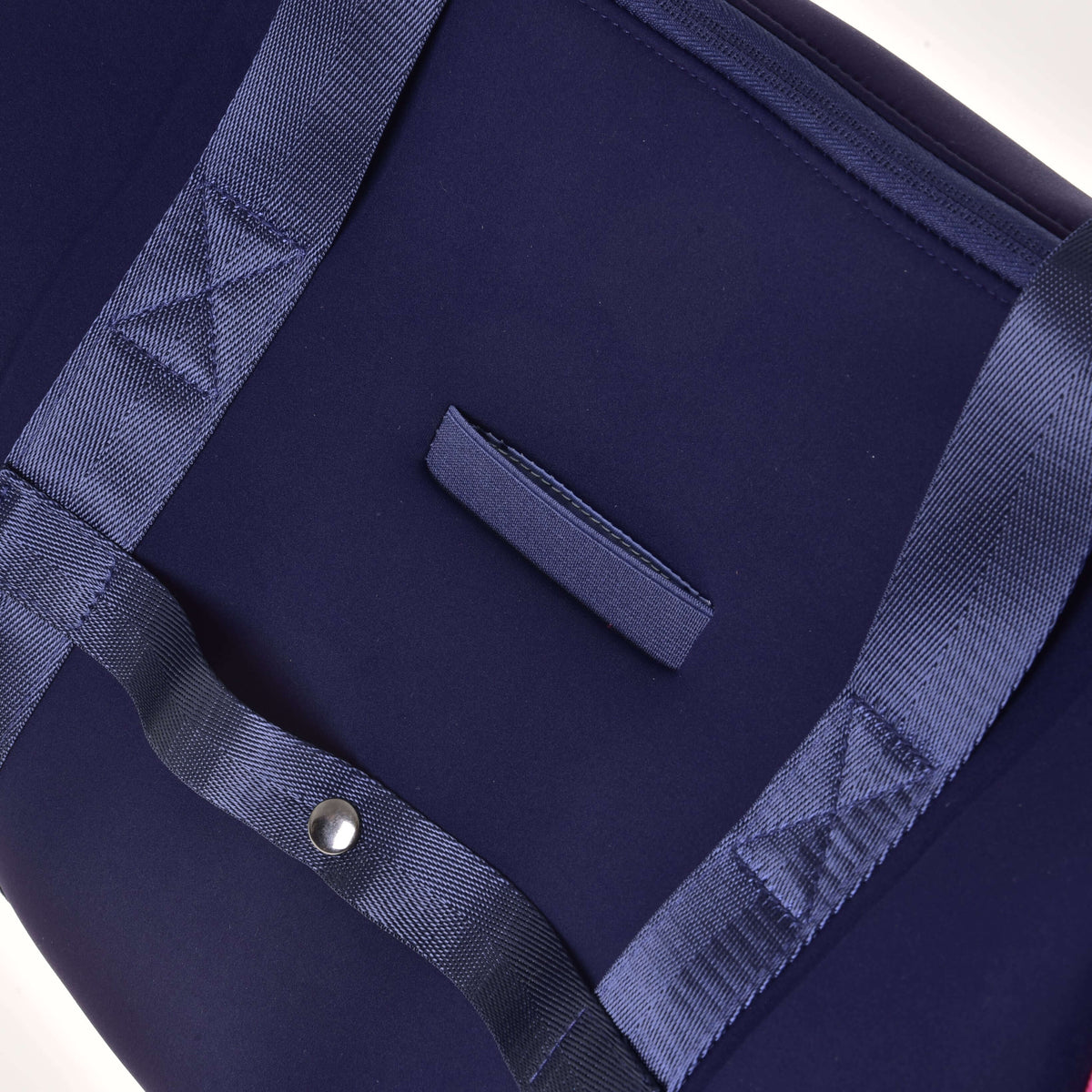 Back of the Hobby Horse Sports bag up close: empty phone slip pocket and a snap-fastened strap for a suitcase handle