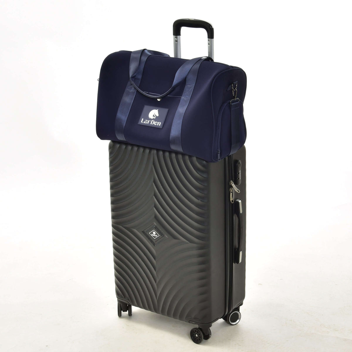 Navy Hobby Horse sports bag with a white LarDen logo sitting on top of a large black rolling suitcase