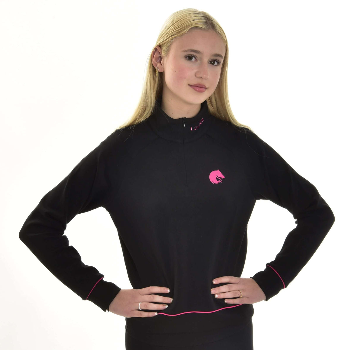 Lyshåret pige med hænderne i siden i den sorte Hobby Horse sweatshirt med lyserødt hestehovedlogo på brystet og lyserød paspel