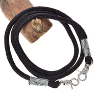 The Hobby Horse LarDen "Hobby Horse - Reins black" features a black braided cord with silver lobster clasps on each end and silver thread wraps, shown coiled on wood—ideal for handmade or paracord reins.