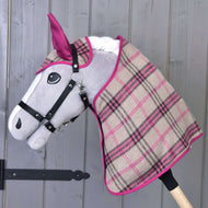 The Hobby Horse LarDen Set Cube Pink features a gray-faced stuffed hobby horse with a black bridle and plaid blanket in beige, pink, and black, displayed against a wooden wall.