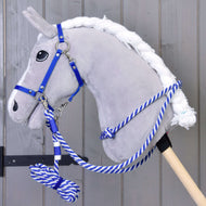 A plush gray hobby horse by Hobby Horse LarDen, featuring the Set Start blue halter, leash, reins, and cordeo, with a blue-and-white lead rope on a wooden stick, stands before a gray wooden wall.