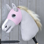 A plush hobby horse by Hobby Horse LarDen wears the Horse Mask without ears Pink—a washable pink mask—on its light gray body, white muzzle, and cream mane. The horse is mounted on a wooden stick against a gray wooden wall.