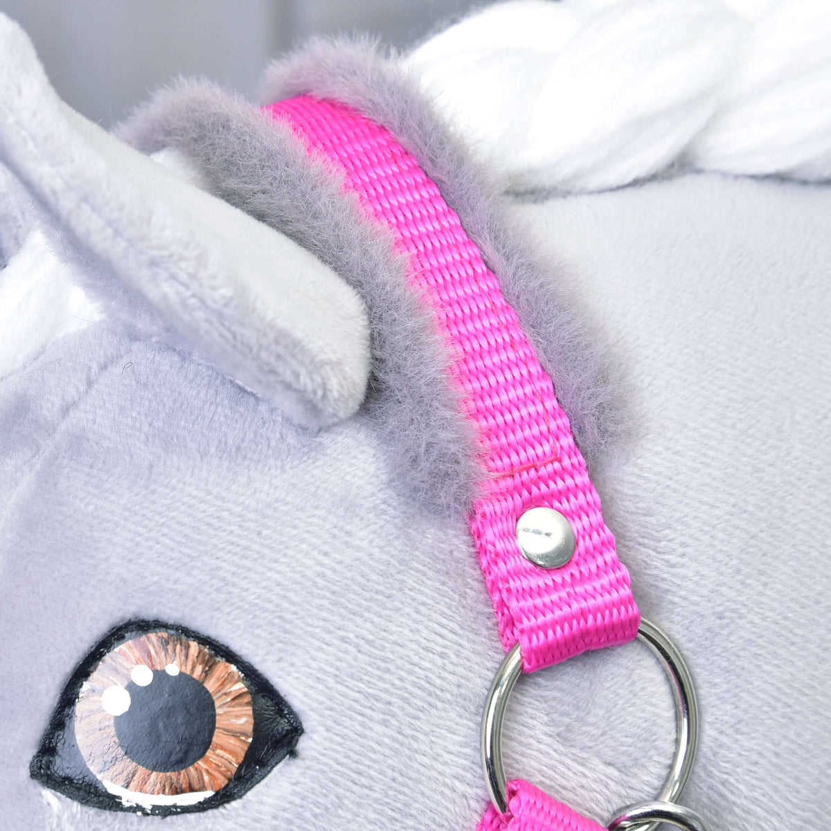 Close-up of the Halter pink with fur by Hobby Horse LarDen on a plush white horse's head, featuring an embroidered eye, soft gray mane, and shiny metal ring—an adorable accessory for imaginative hobby horse play.