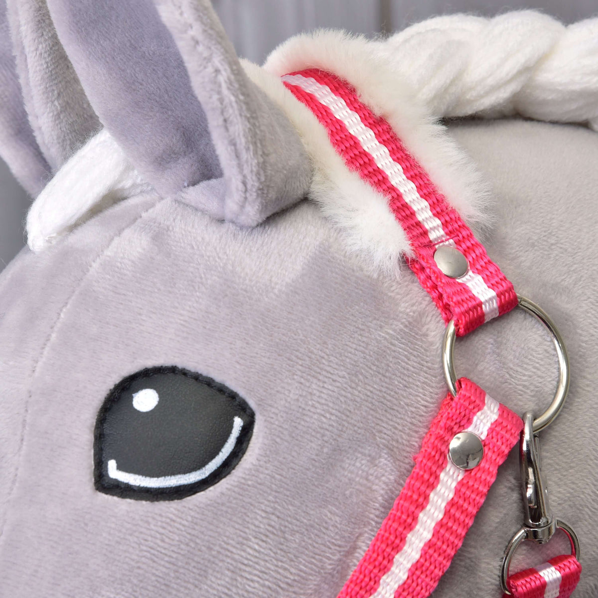 Close-up of a plush gray unicorn head with a white mane, black and white embroidered eye, and a Hobby Horse LarDen Halter red stripe with fur.