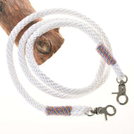 The Reins white by Hobby Horse LarDen features metal clasps at both ends and rainbow-colored thread near each clasp, coiled on wood against a white background—evoking the look of high-quality bitless bridle reins.
