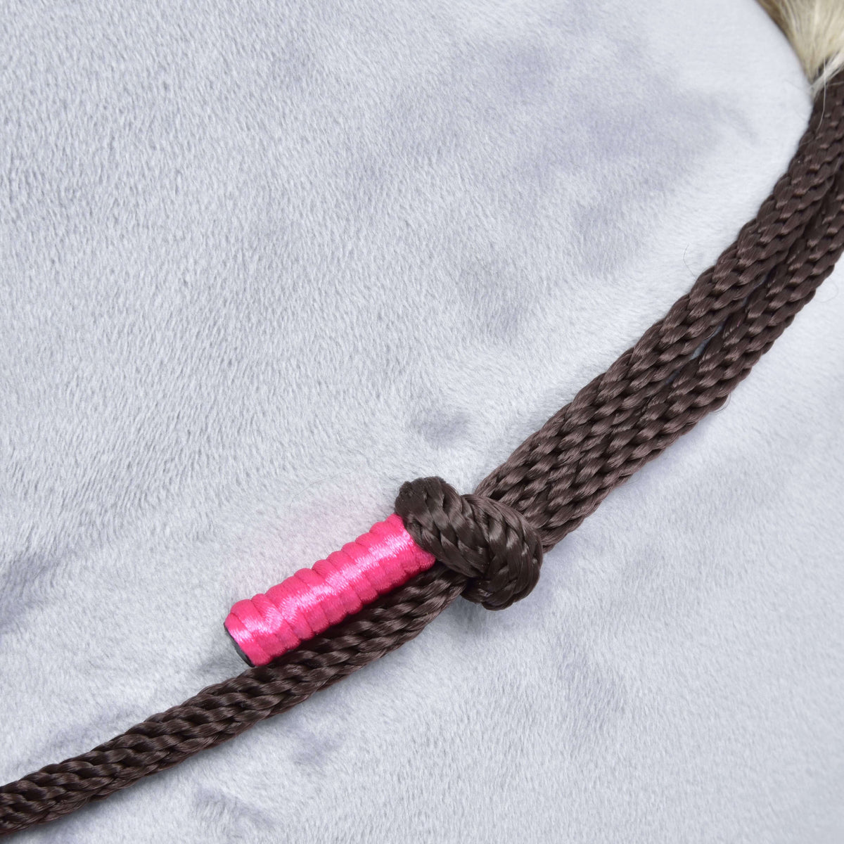 Close-up of the Hobby Horse LarDen Rope set Noir Cocoa, a brown braided rope halter knotted around a light gray horse’s neck, with part of the rope wrapped in bright pink tape.