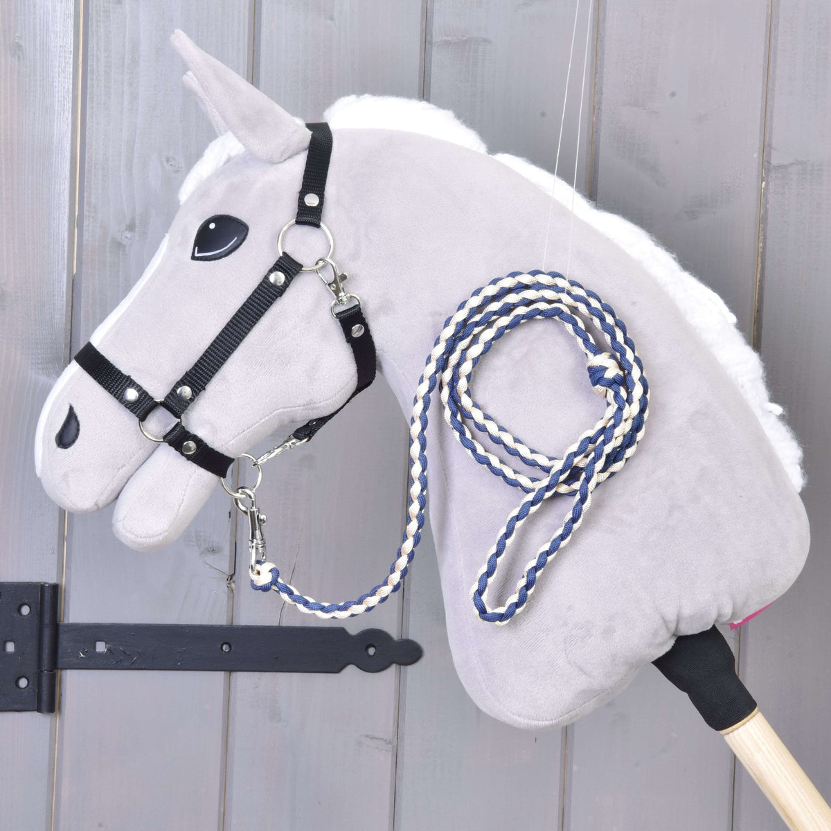 Navy and cream braided lead rope clipped to the black halter of a grey Hobby Horse with white mane