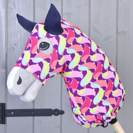 The Hobby Horse LarDen Hobby Horse Protective suit Bird (Lycra) features a vibrant pink, yellow, green, and blue bird-patterned Lycra cover on a wooden stick, shown against a gray wooden wall background.