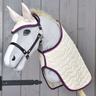 The Hobby Horse LarDen Set Supreme Crema features a plush gray-faced hobby horse with a white muzzle and ears, dressed in a quilted cream blanket and matching ear bonnet with purple trim, displayed on a wooden wall.