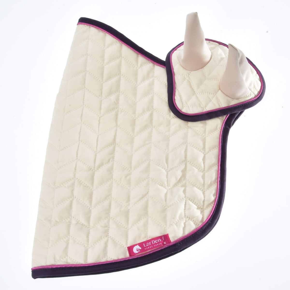 The Set Supreme Crema by Hobby Horse LarDen is a quilted cream saddle pad with dark trim, pink piping, two raised horn-like ends resembling a hobby horse, and a pink LexDen Collection label.
