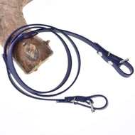 The Hobby Horse LarDen "Reins rubberized Dark purple" is shown coiled on a white surface, partially draped over textured wood, evoking the elegance of classic equestrian bridles.