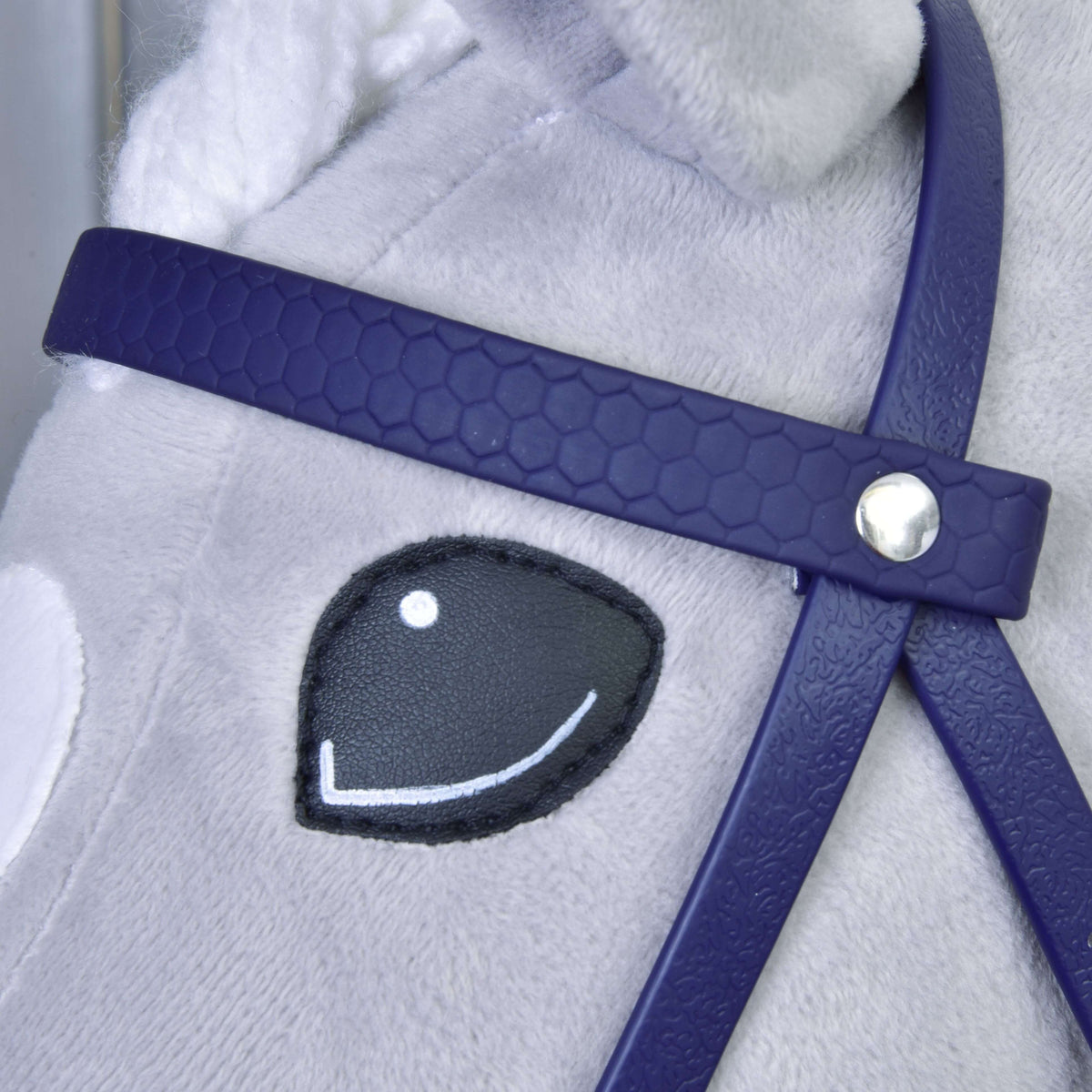 Close-up of the dark purple honeycomb browband with silver rivet beside the smiling eye of a grey Hobby Horse