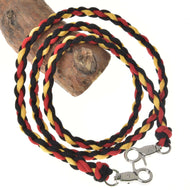 The Hobby Horse LarDen Reins Flag is a braided polypropylene rope leash in black, red, and yellow, coiled around wood and inspired by handmade reins. It features silver metal clasps at both ends.