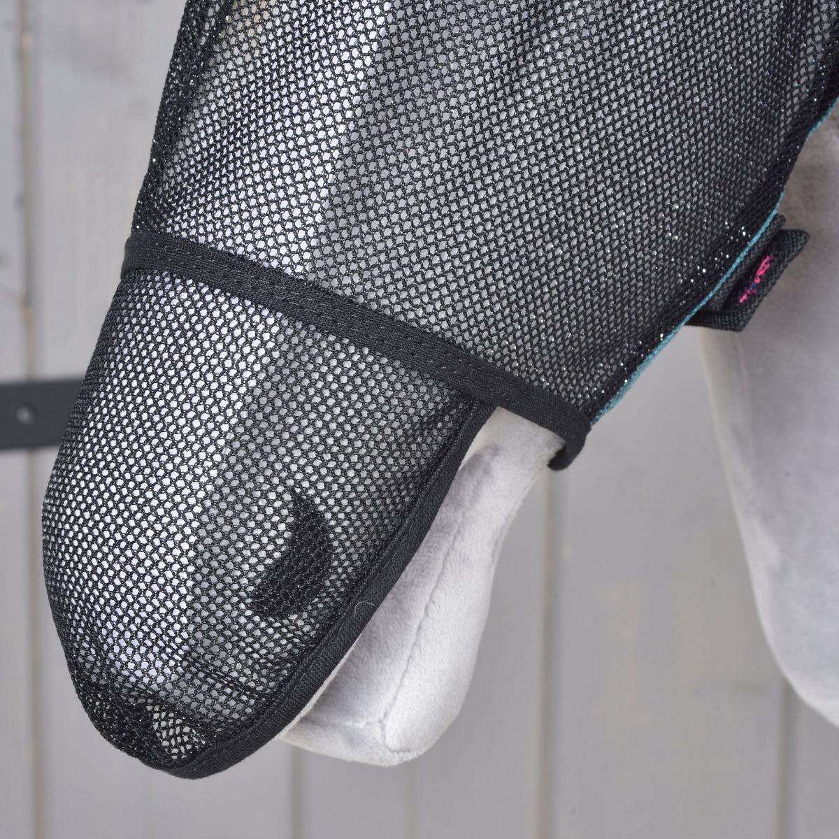 Close-up of the black mesh nose piece of the fly mask covering the muzzle and nostril of a grey Hobby Horse