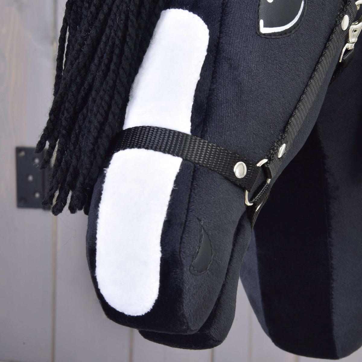 A close-up of Hobby Horse LarDen’s Freya with Black Halter, featuring a yarn mane, fabric bridle, and white face patch inspired by the Irish Cob, set against a neutral background.