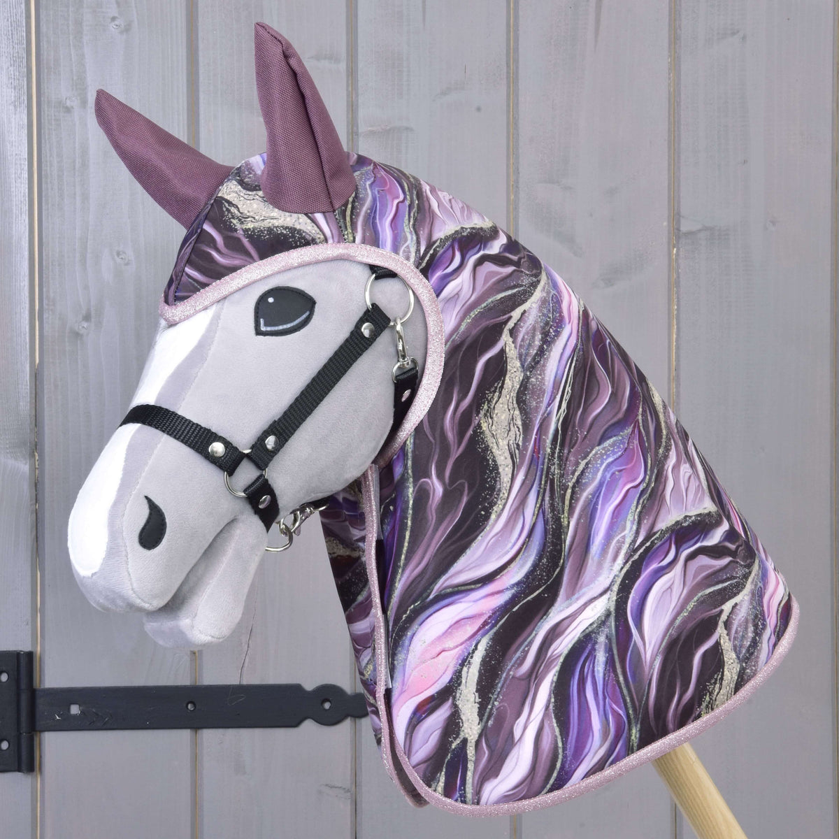 The Hobby Horse LarDen Raincoat Galaxy Space features a plush hobby horse head with a black bridle and a hood in swirling purple, black, and white patterns—ideal for any adventure, rain or shine.
