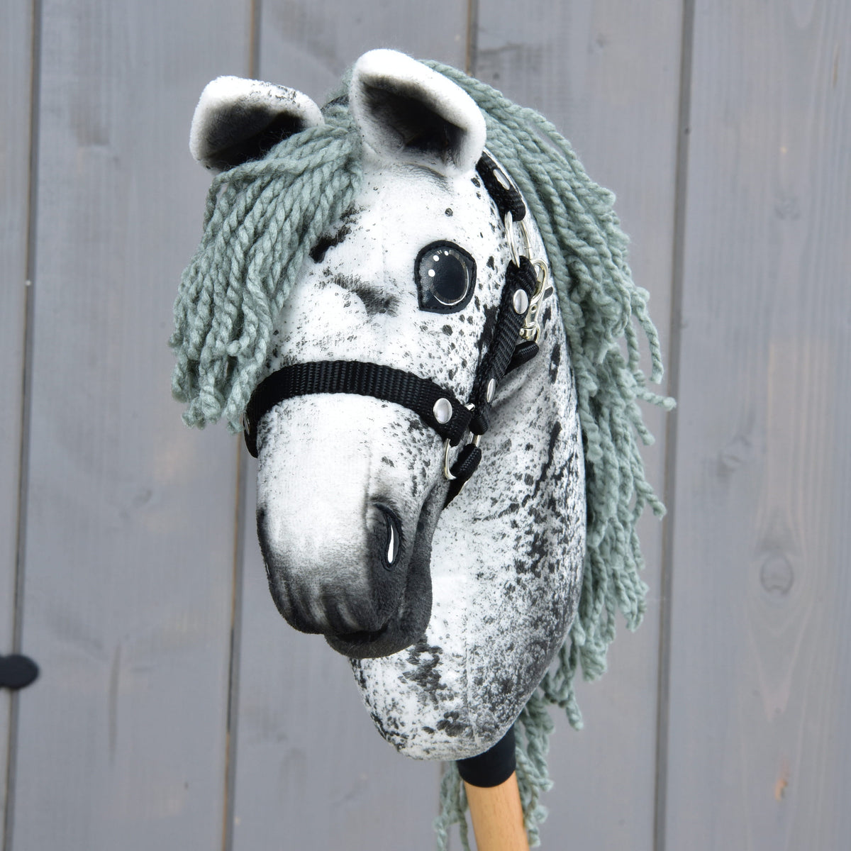 Kæphesten Hobby Horse Hazel set forfra med hvide ører, grågrøn pandelok af garn og sort grime med sølvfarvede nitter
