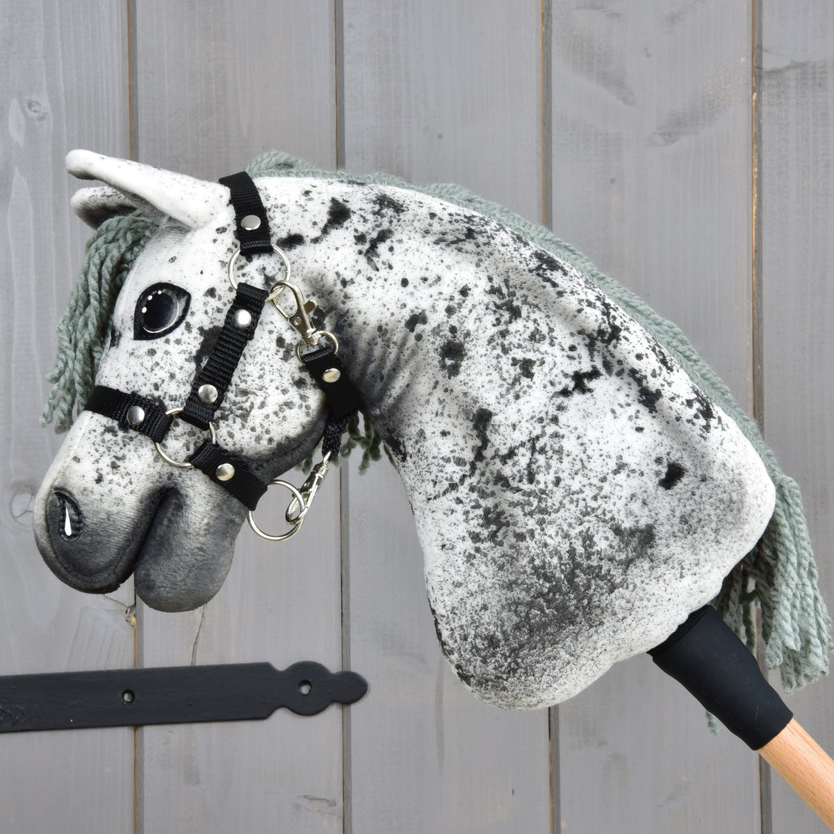 Kæphesten Hobby Horse Hazel set fra siden: hvid hals med sorte prikker, grimens karabinhage og trækæp med sort manchet
