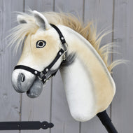 A close-up of the Hobby Horse LarDen "Honey Pearl" in size S, a beige and white plush Oldenburg-inspired horse with a black halter, fluffy mane, and friendly detailed face, set against a wooden panel background.