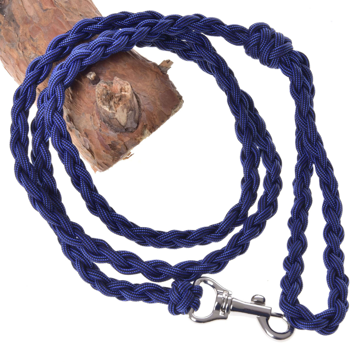 The Hobby Horse LarDen Knitted Lead Rope Royal Blue, featuring a strong carabiner, is coiled on a tree branch.