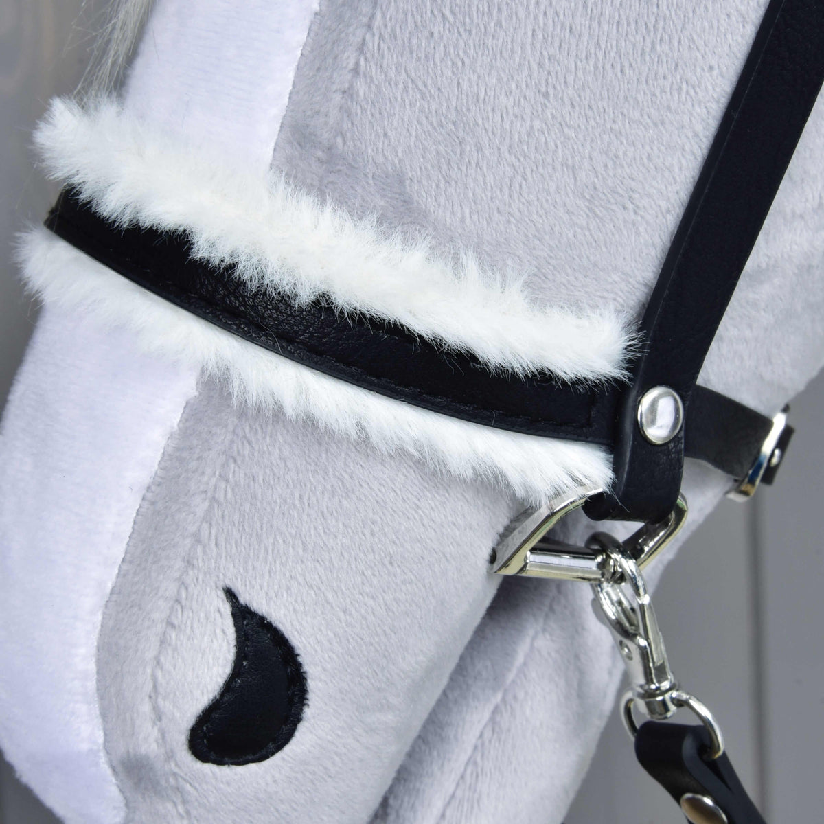 Close-up of Hobby Horse LarDen's Complete bridle with fur: a soft, light gray plush horse head with leatherette bridle, white faux fur trim, black crescent-shaped nostril detail, and a lightly textured surface.