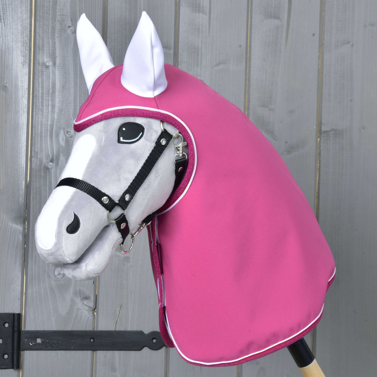Grey Hobby Horse in a black halter wearing the Raincoat LarDen, raspberry pink with white ears and white piping