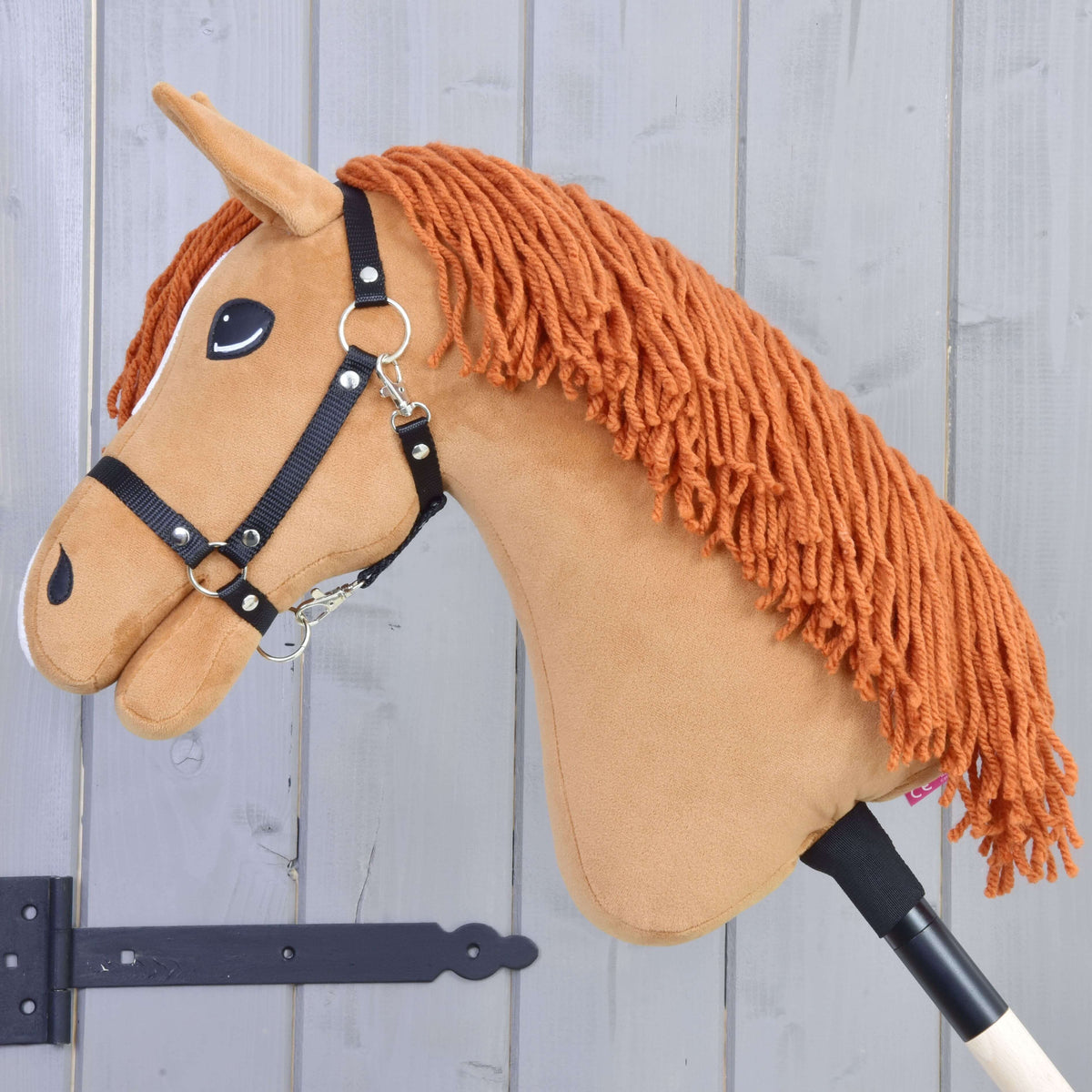 The Hobby Horse LarDen "Little Angel with Black Halter" features white accents and an orange yarn mane, mounted on a stick and set against a light gray wooden background.