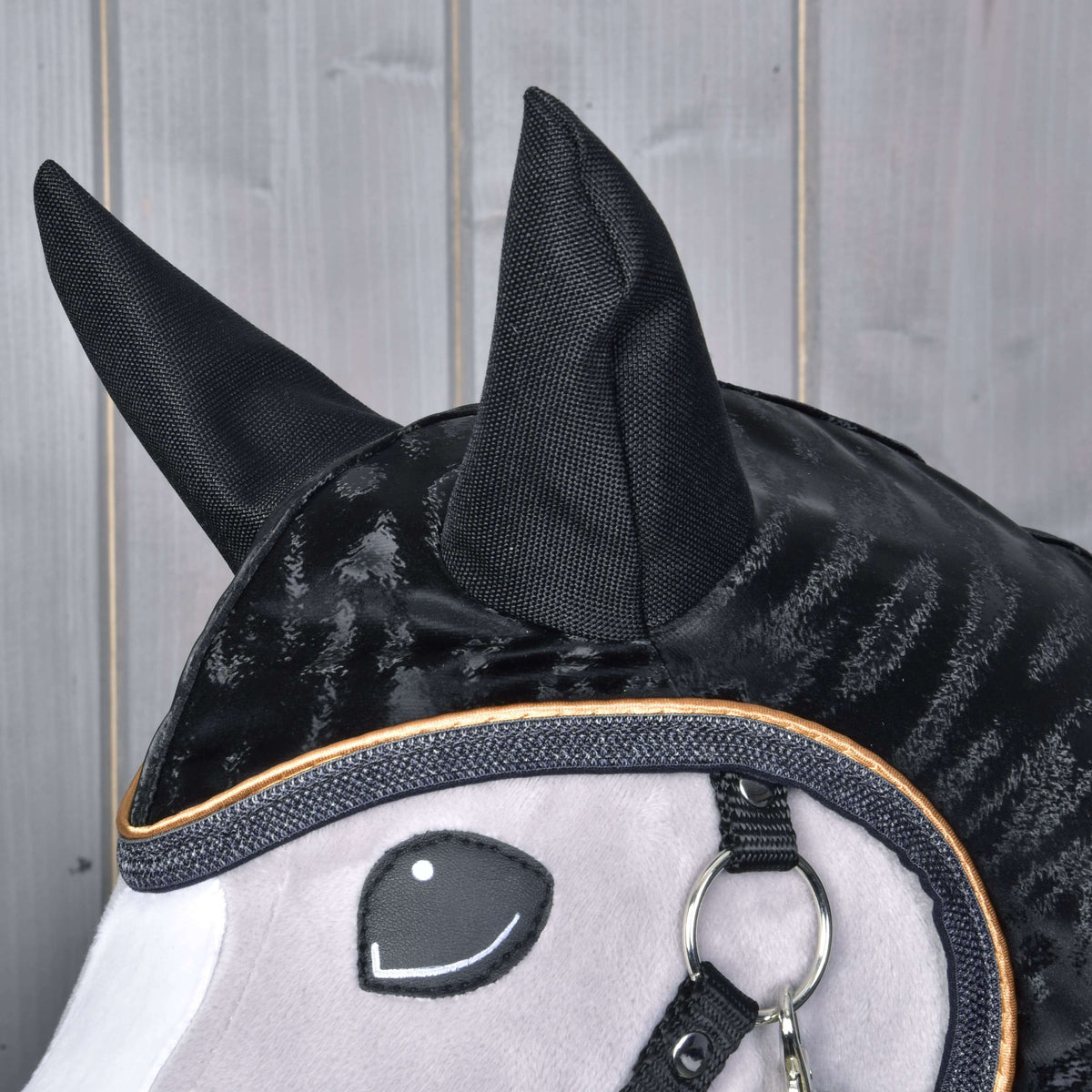 Close-up of the black ear covers and glossy striped fabric with grey binding and gold piping around the face opening