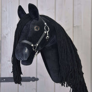 The Hobby Horse LarDen Maximus with a black halter is a plush black Friesian hobby horse with a long black mane, mounted on a wooden stick and shown against a light wood-paneled background.