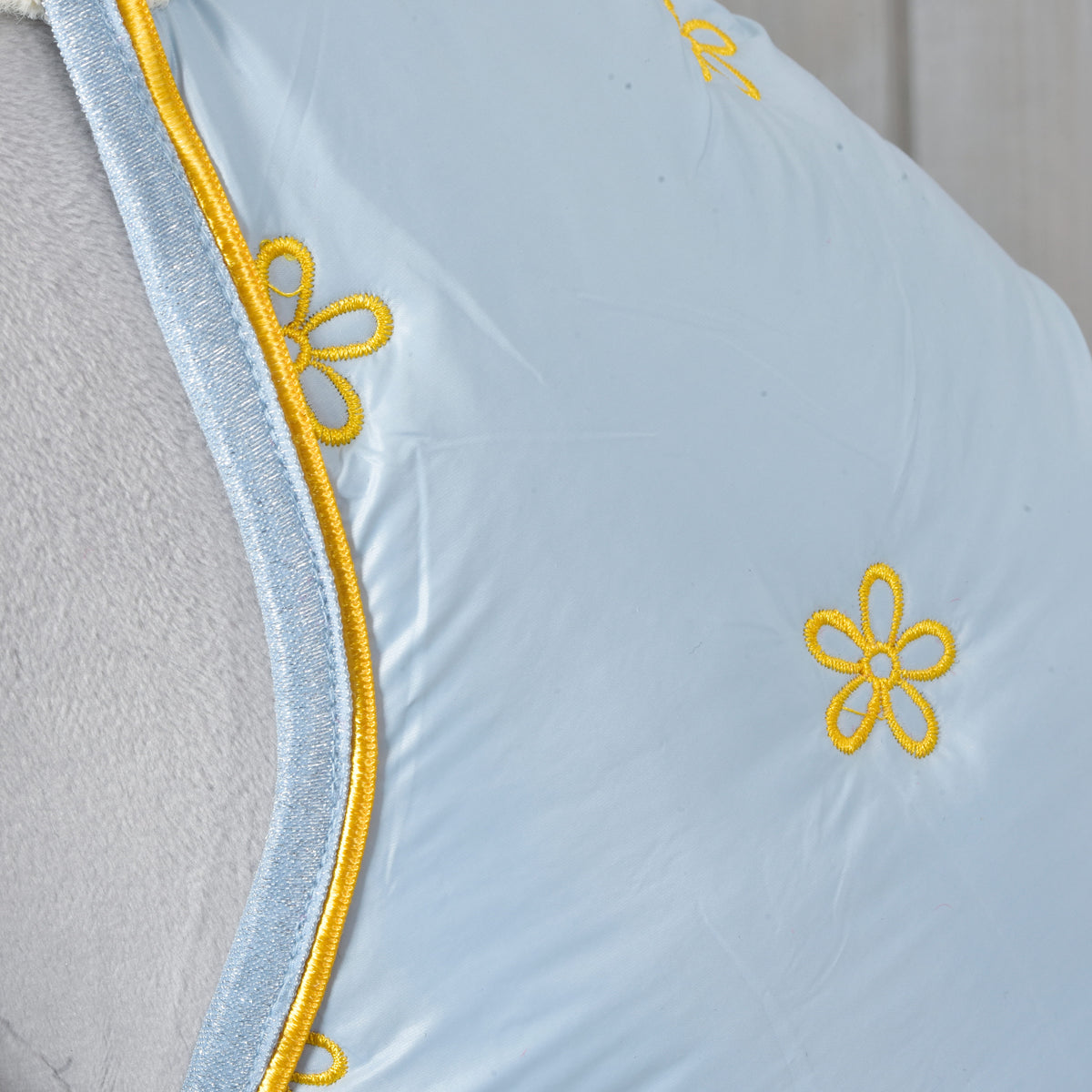 Close-up of yellow embroidered flowers and yellow piping on the pale blue Hobby Horse Stable Blanket Misty