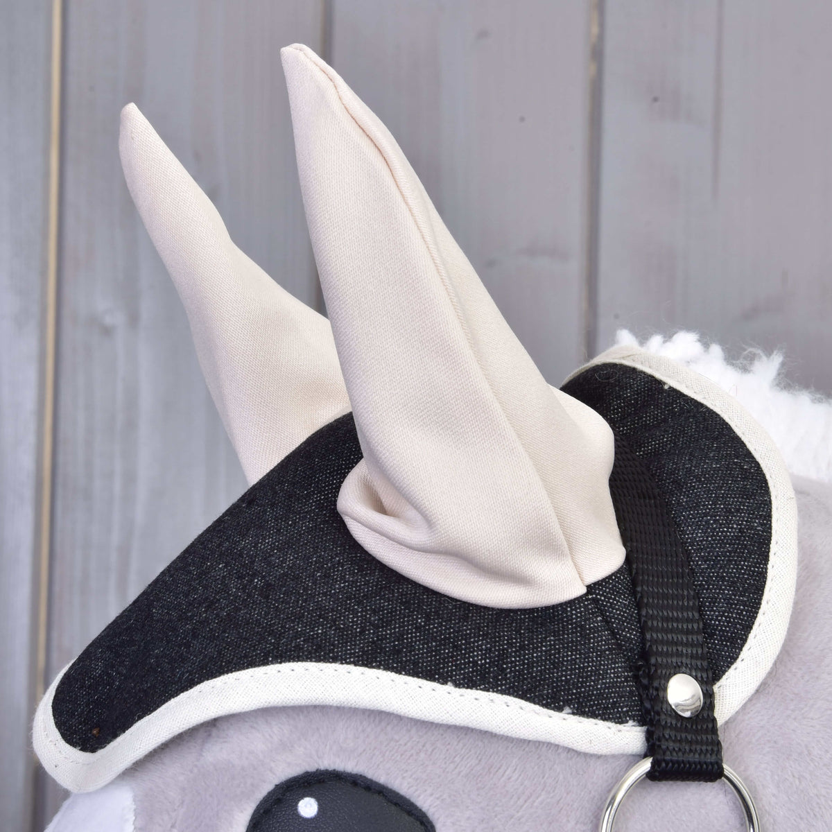 Close-up of the gray plush Set Blue Denim Hobby Horse by Hobby Horse LarDen, featuring a black and white fabric bridle and soft cream-colored ears—a charming decoration for any fan.